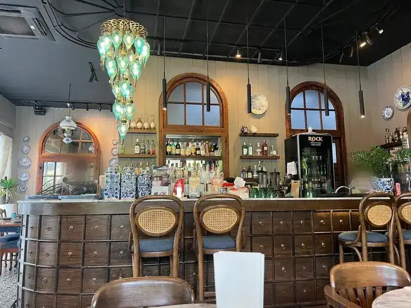 The bar counter, built from rows of small wooden drawers, under arched windows and a turquoise glass chandelier
