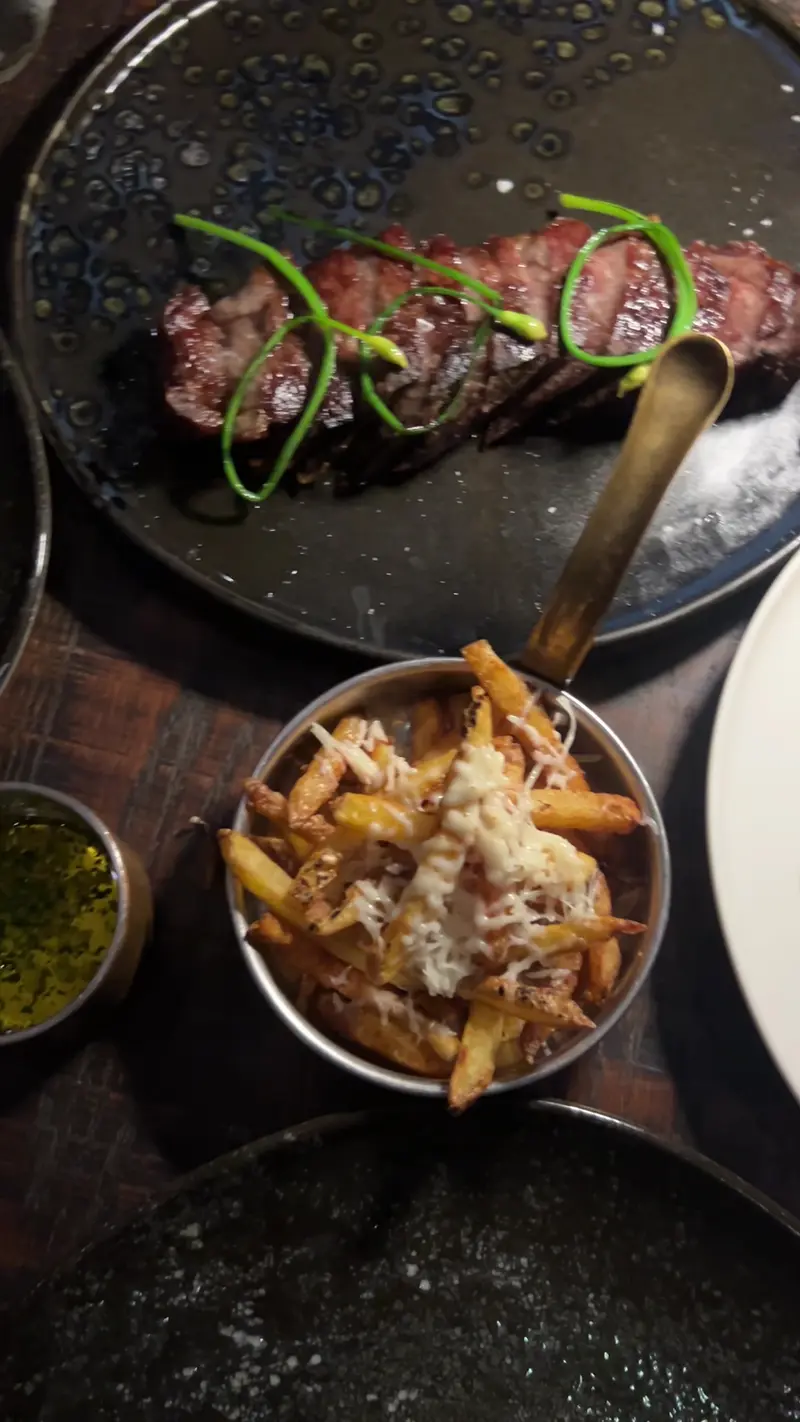 Sliced steak and a pan of fries with grated cheese, seen from above / สเต๊กหั่นชิ้นกับเฟรนช์ฟรายส์โรยชีส มุมมองจากด้านบน