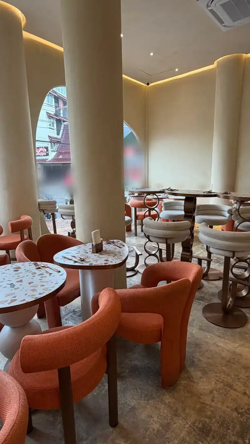 The dining room: orange chairs, terrazzo tables and tall round pillars, with oval windows onto the street