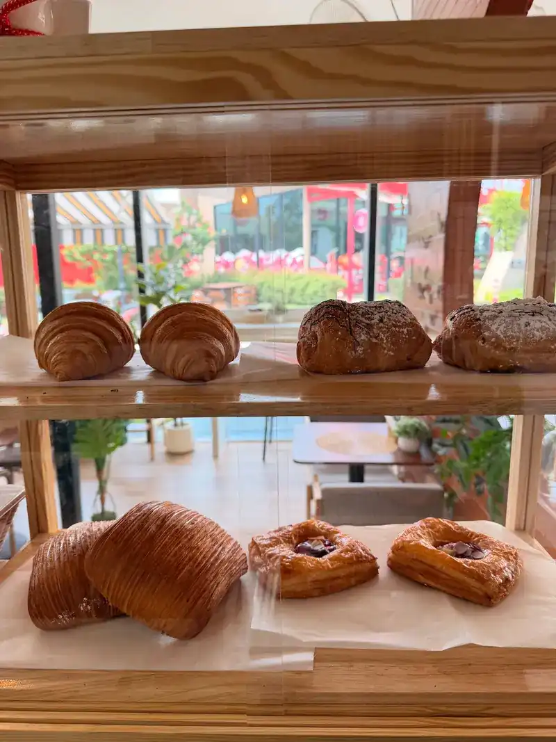 Croissants and Danish pastries on a wooden shelf by the window