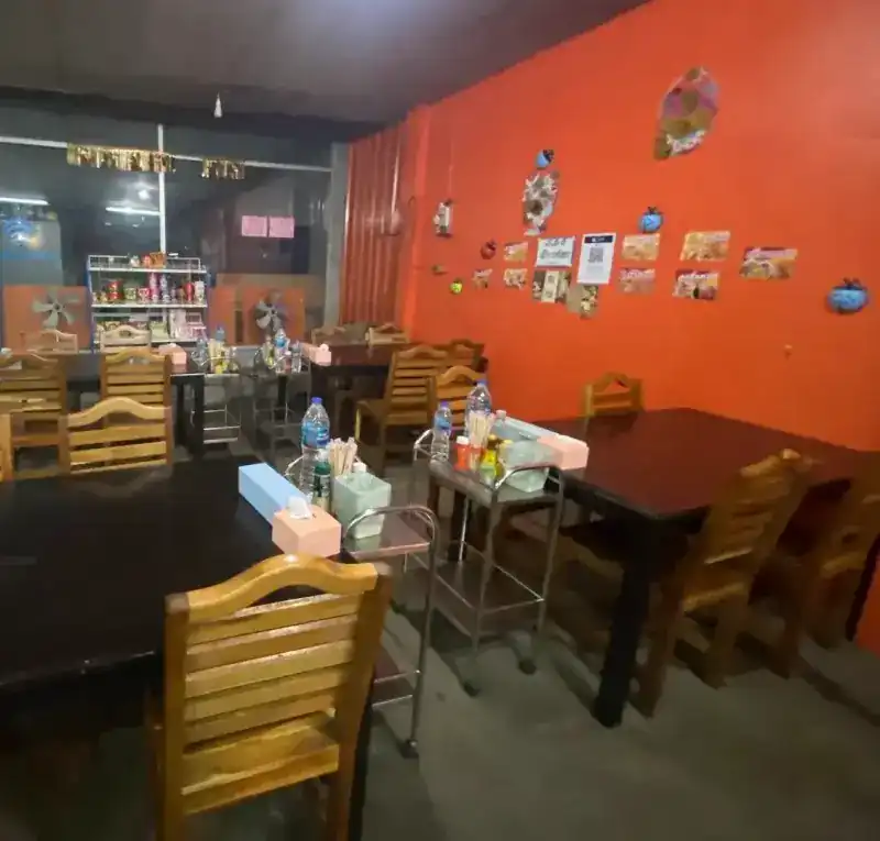 The dining room: dark wooden tables and an orange wall