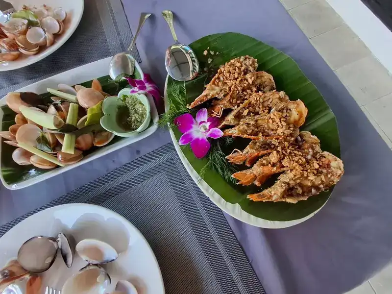 Steamed clams with lemongrass and a green dipping sauce, beside fried prawns topped with crisp garlic