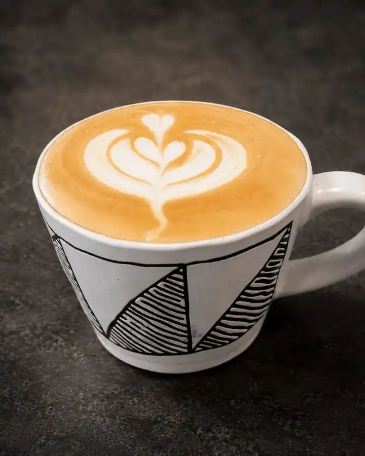 Flat white with latte art in a hand-drawn black and white mug