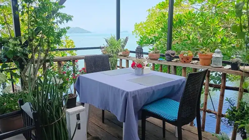 A table for two at the wooden rail, potted plants and islands beyond