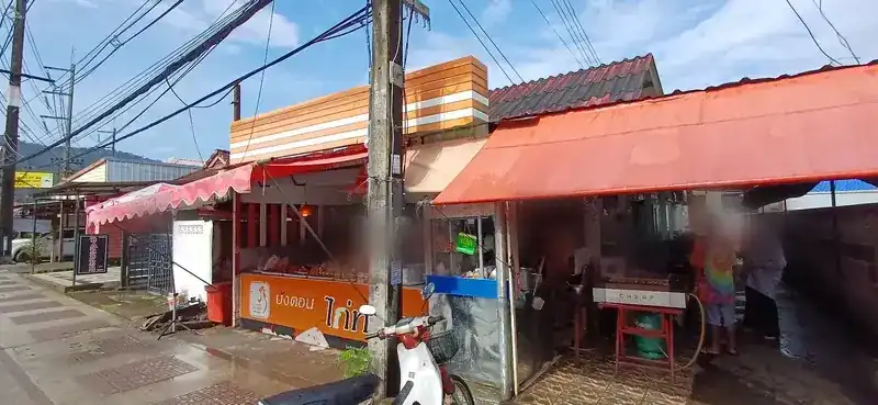 The shop from the street: an orange counter with the sign บังตอน ไก่ทอด, under orange and red awnings