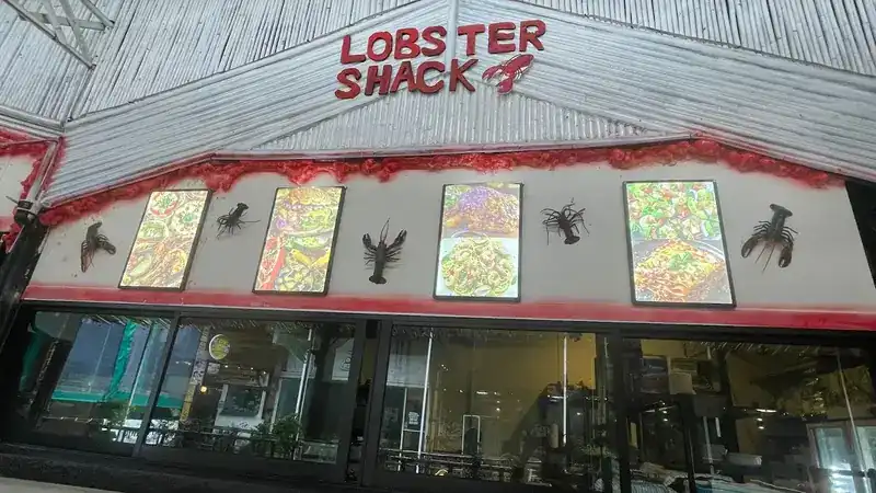 The front of Lobster Shack: red letters on white bamboo, framed food pictures and lobster cut-outs