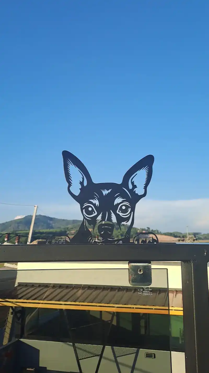 A metal dog cut-out on the rooftop rail against the sky