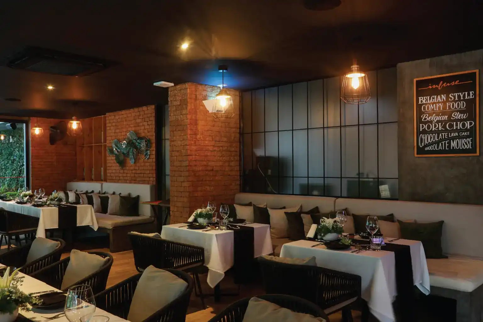The dining room at Infuse: brick pillars, white tablecloths, hanging lamps and a blackboard on the wall