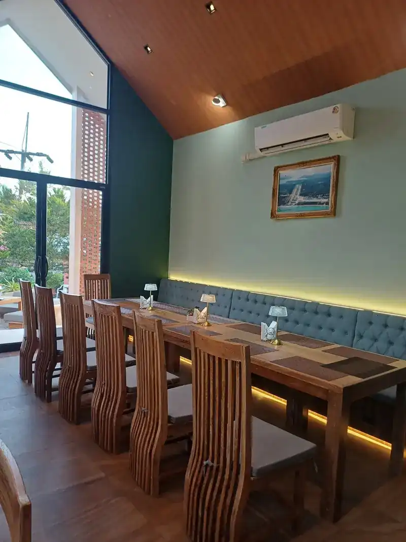 A long wooden table with tall slatted chairs under a high wooden ceiling