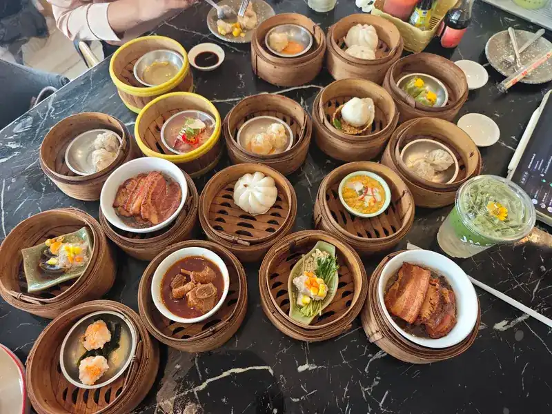 Dim sum baskets and bowls of braised pork belly on a marble table