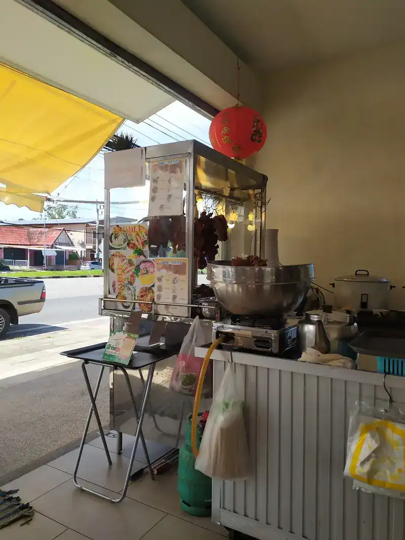 The shop's roast-meat cart under a yellow awning and a red lantern, with the road outside