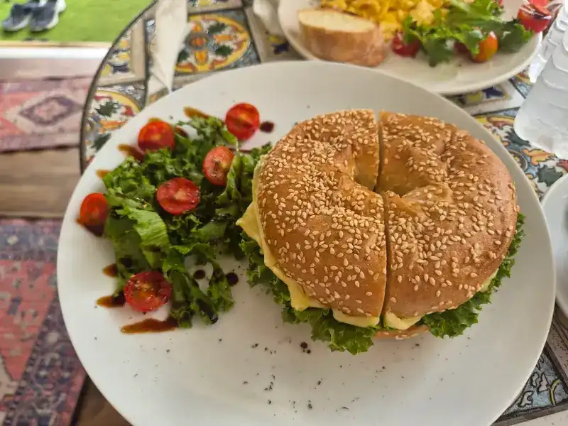 Sesame bagel sandwich with cheese and a side salad