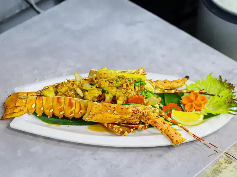 A whole lobster served in its shell with fried garlic, carved carrot and lemon
