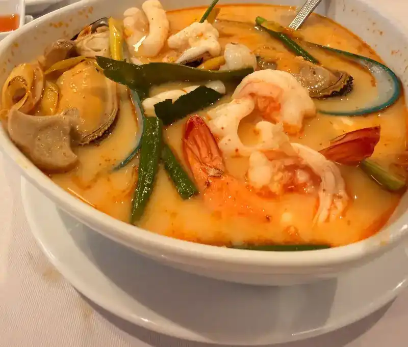 Creamy tom yum with prawns, mussels and squid in a white bowl