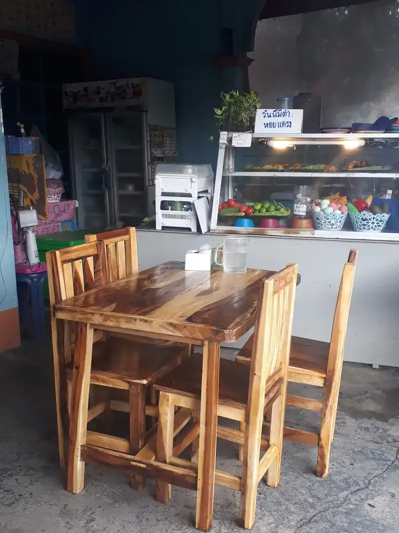 A wooden table in front of the glass counter and the shop's sign