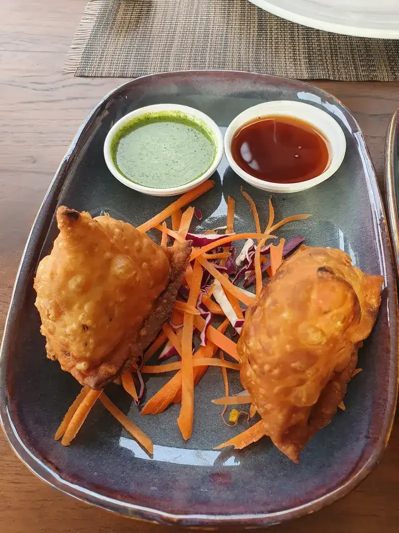Two samosas with two dipping sauces