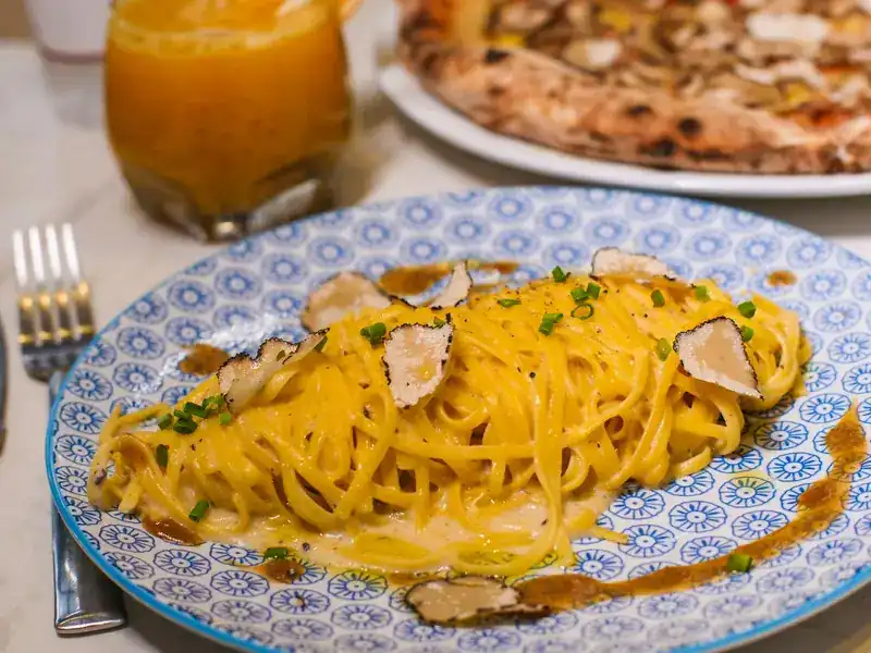 Thin egg pasta with truffle shavings on a blue patterned plate