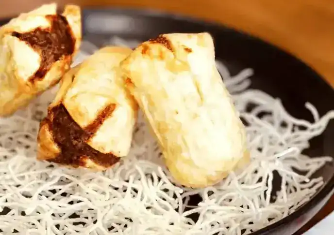 Three fried dim sims on a nest of crispy noodles