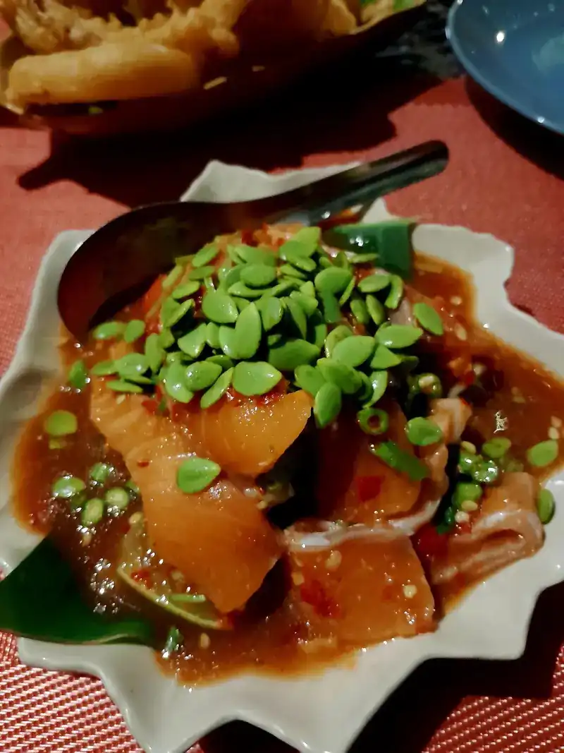Raw salmon in a spicy red dressing on a leaf-shaped plate