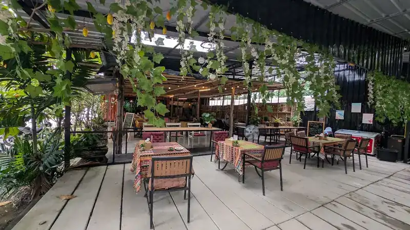The covered deck, with striped tablecloths and vines hanging from the roof