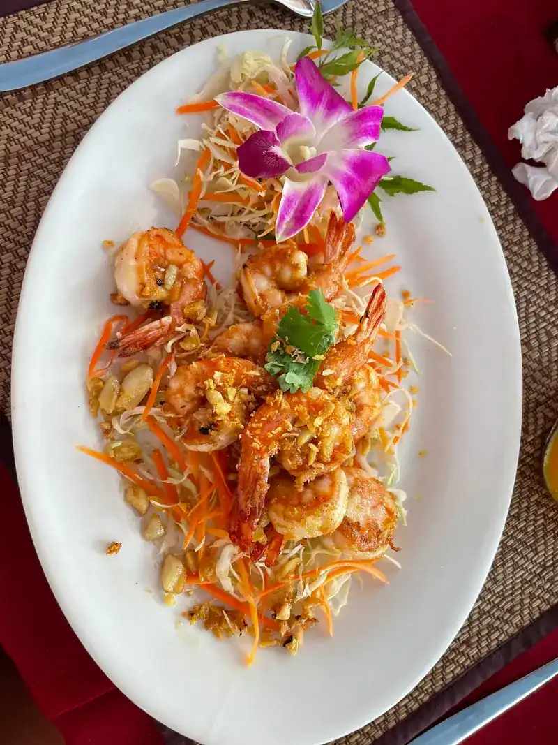 Prawns topped with fried garlic on a long plate with an orchid / กุ้งโรยกระเทียมเจียวบนจานยาว แต่งด้วยกล้วยไม้