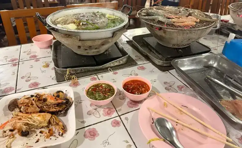 A table set with the pan, the grill, two dipping sauces and pink plates