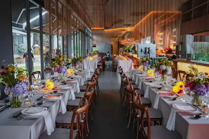 Long tables dressed in white with flowers for a celebration in the dining room