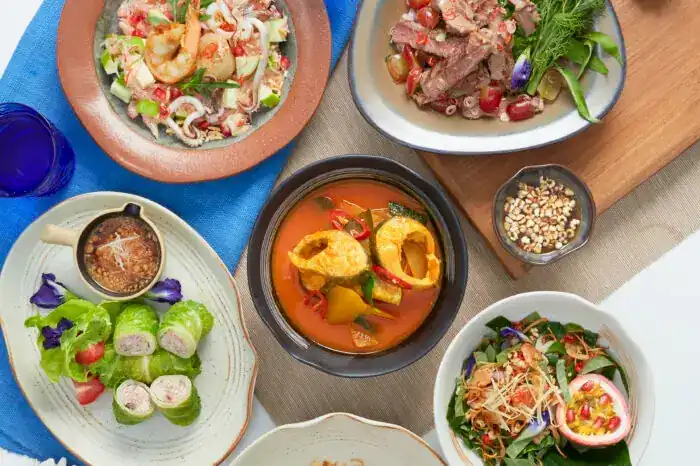 Thai dishes on the table: a curry, salads and wrapped rolls