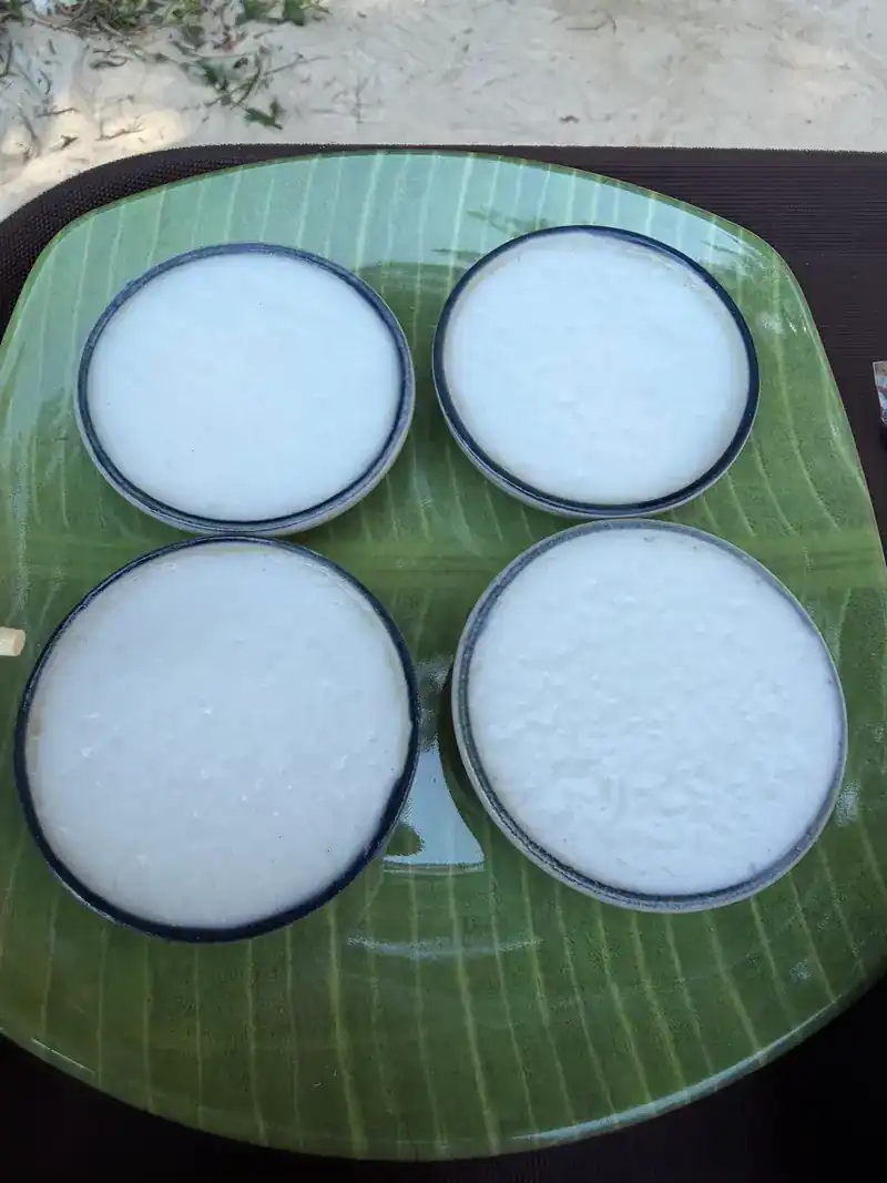 Four cups of khanom thuay, steamed coconut cups, on a leaf-shaped plate