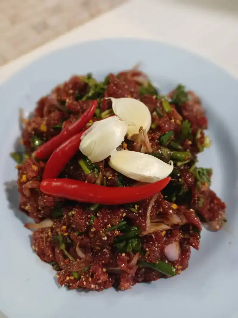 Larb of minced meat with herbs, topped with fresh red chillies and garlic