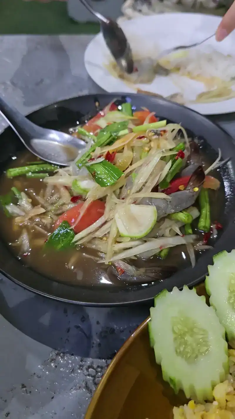 Papaya salad with long beans and tomato in a dark bowl