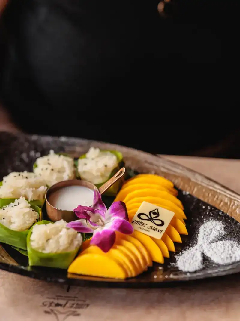 Mango with sticky rice in banana-leaf cups, topped with an orchid