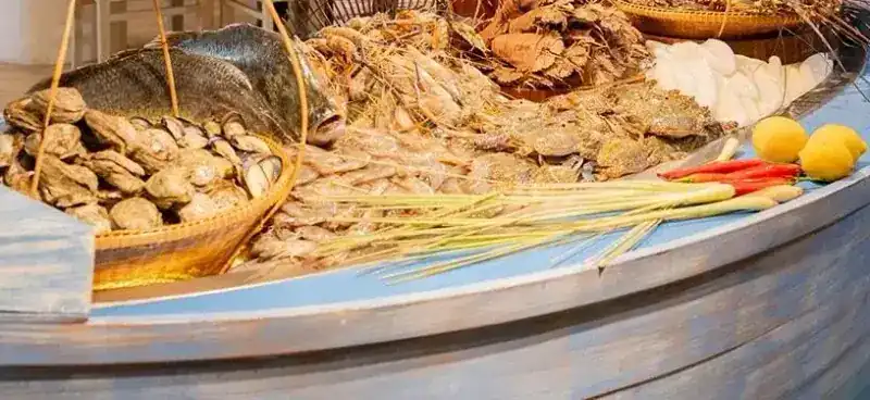 Fish, shellfish, crabs, tiger prawns and lobsters laid out in a painted wooden boat