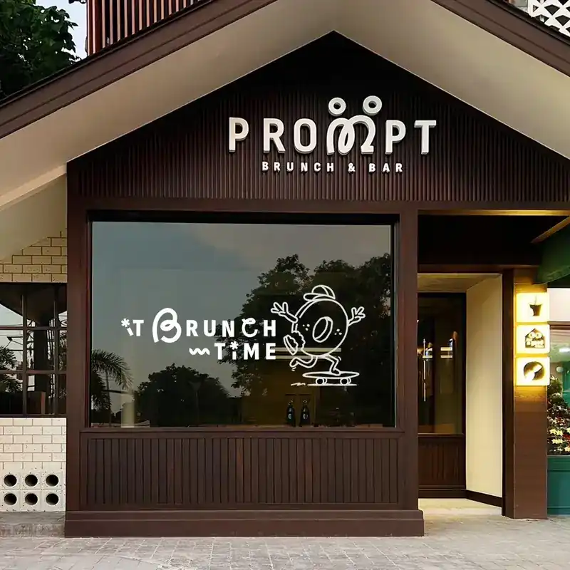 The front of PROMPT: a dark wooden house with a white sign and a big window