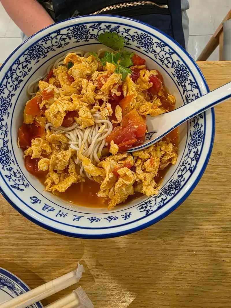 Noodles under scrambled egg and tomato
