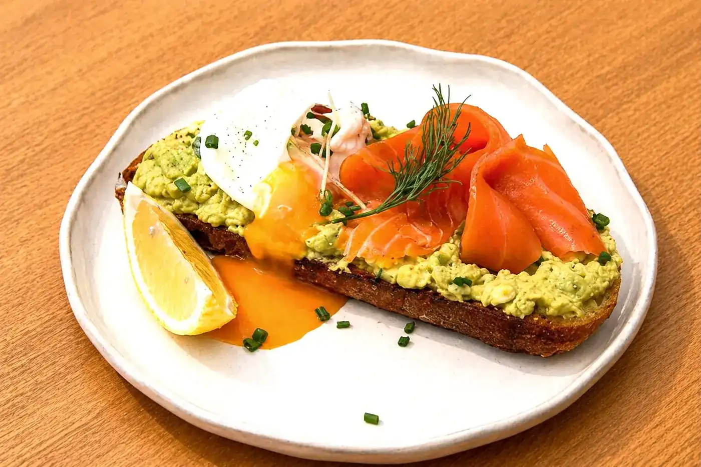 Salmon avocado smash on sourdough with a poached egg, chives and lemon