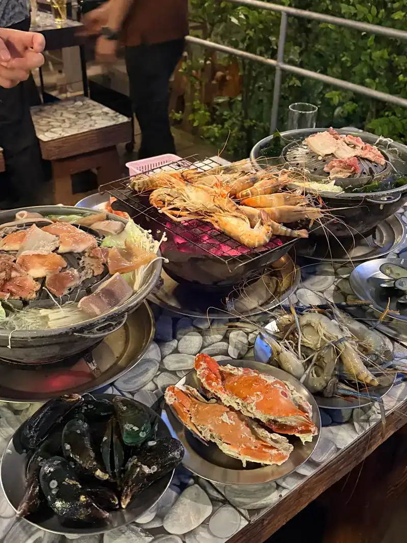 A table spread with crabs, mussels, prawns on a grill and a pan of seafood