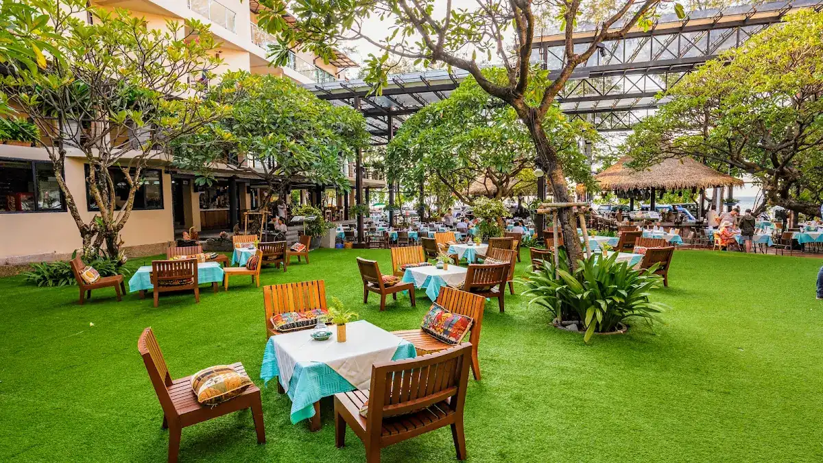 Wooden chairs and tables with white and teal cloths on the lawn of the courtyard, under trees