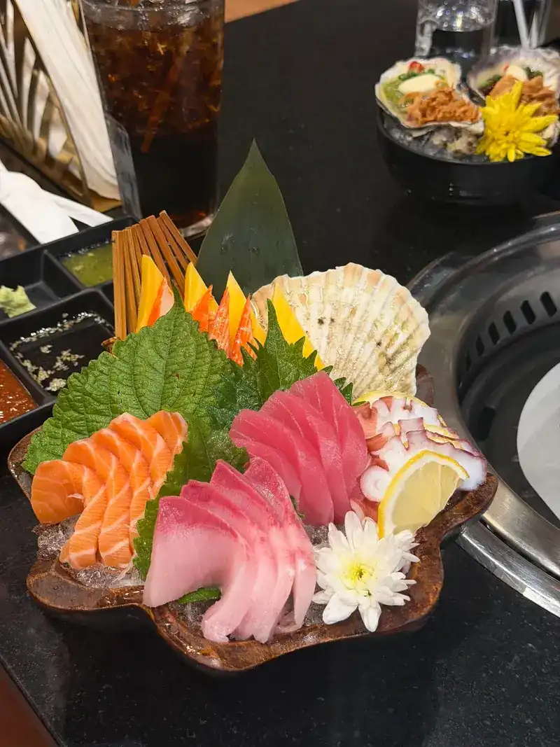 A sashimi platter on ice with shiso leaves and a lemon slice