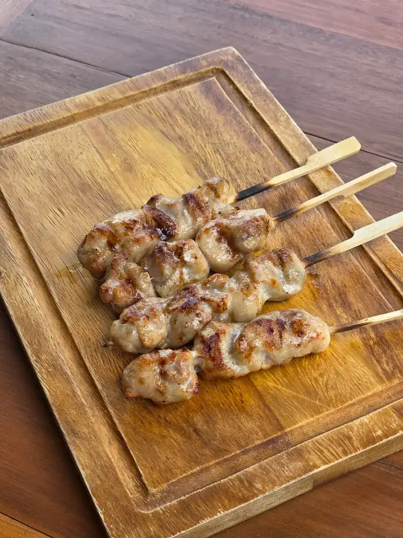 Four grilled skewers on a wooden board