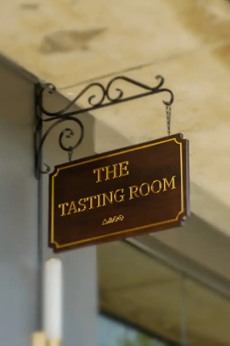 The wooden sign of the Tasting Room hanging from an iron bracket