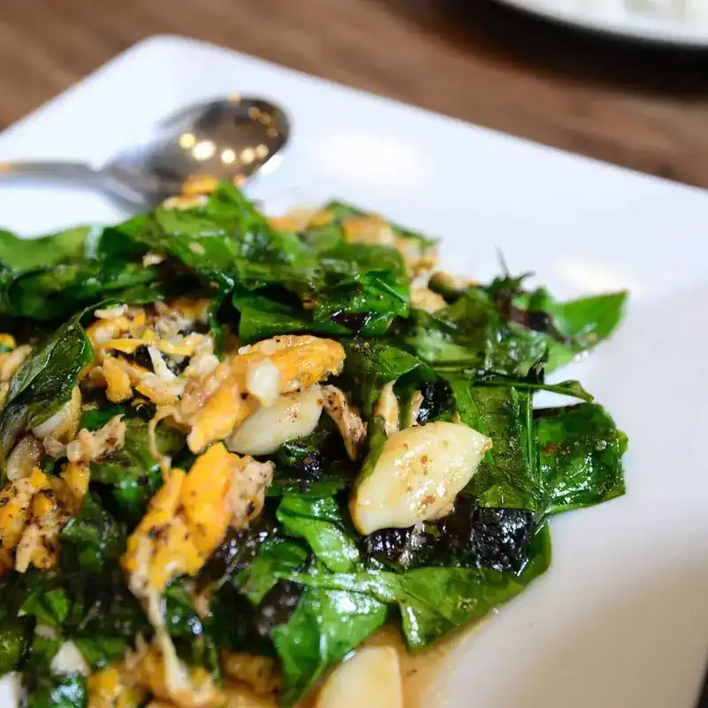 Green leaves stir-fried with egg on a white plate