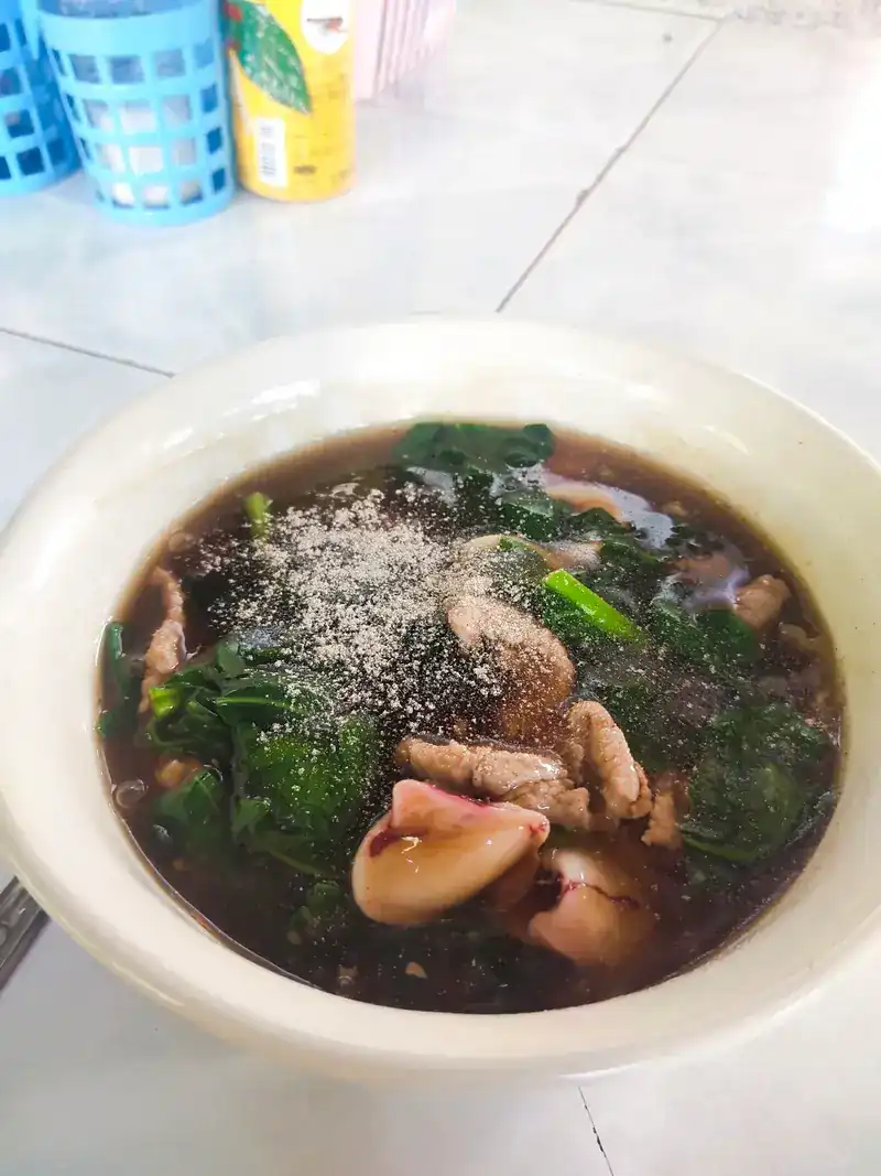 A guest's bowl: pork and greens in a dark broth