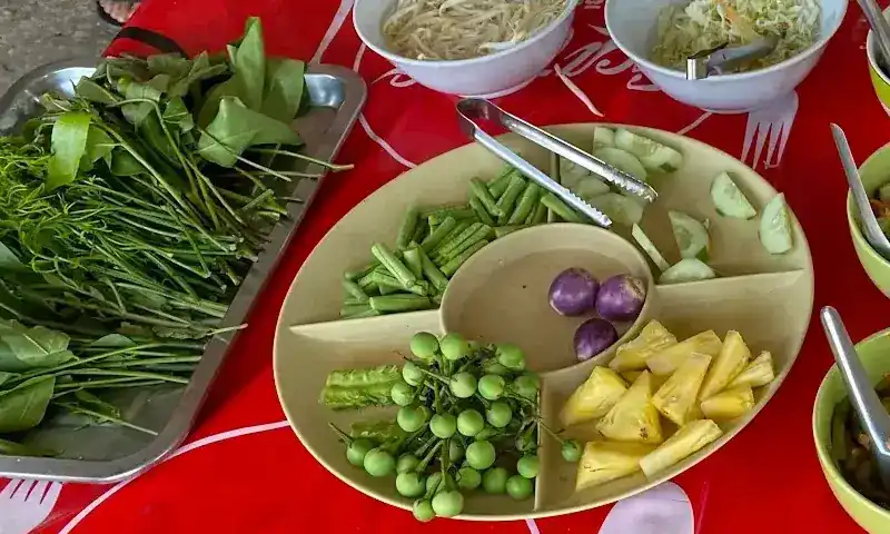 The vegetable table: leafy greens, long beans, cucumber, pea aubergines, small aubergines, winged beans and pineapple
