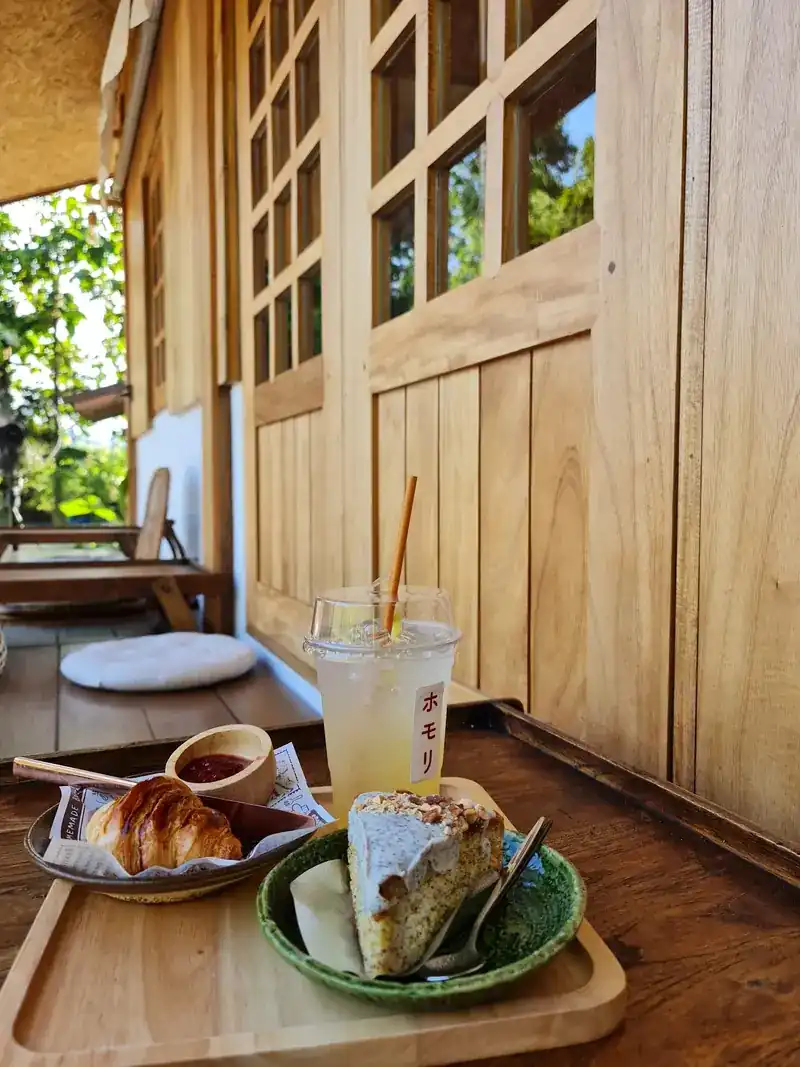 A slice of cake, a croissant and an iced drink on a tray on the veranda