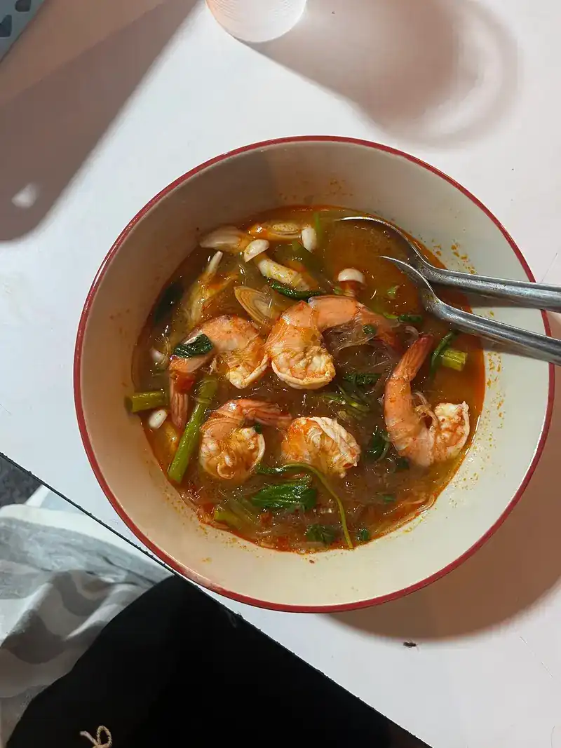 Tom yum with prawns in a red-rimmed bowl