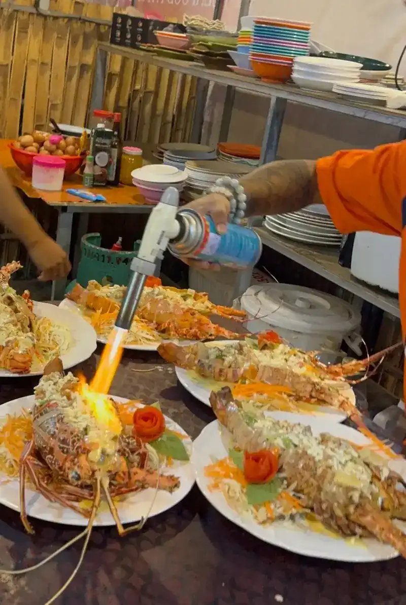 Plated lobsters with a topping, one being finished with a torch flame