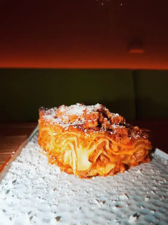 A slice of baked lasagne dusted with grated cheese