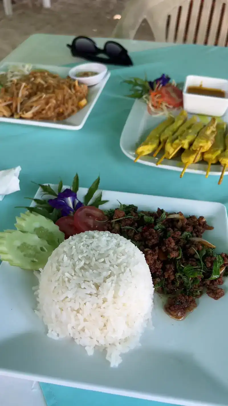 Pad thai, satay and a holy-basil stir-fry with rice on a turquoise tablecloth