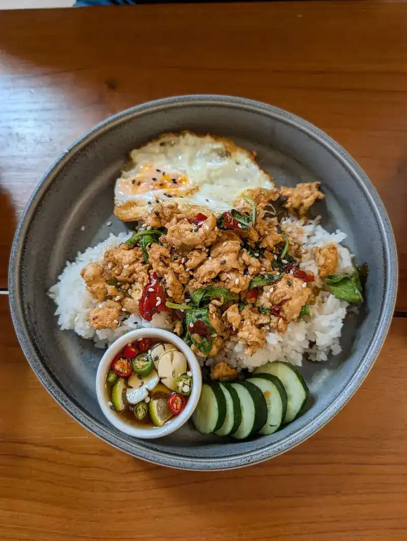 Holy basil stir-fry on rice with a fried egg, cucumber and chilli fish sauce